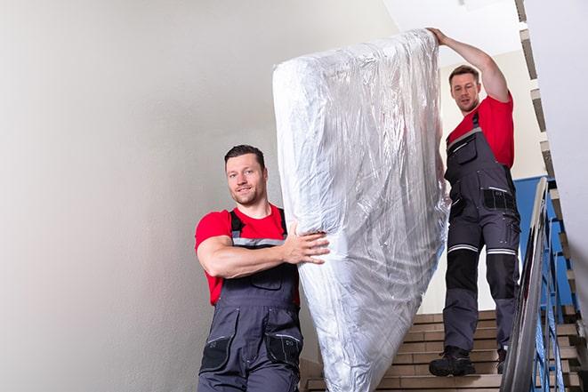 two workers hauling a box spring out of a building in Kansas City